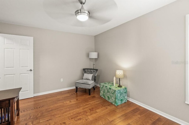 living area with light wood finished floors, a ceiling fan, and baseboards