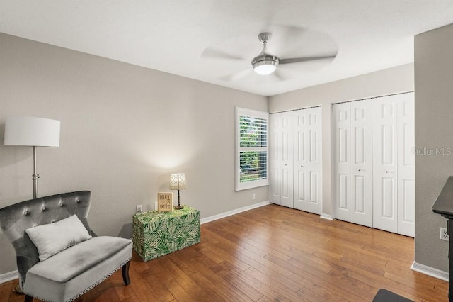 sitting room with a ceiling fan, baseboards, and hardwood / wood-style floors