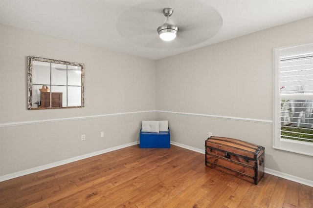 interior space with wood-type flooring, ceiling fan, and baseboards