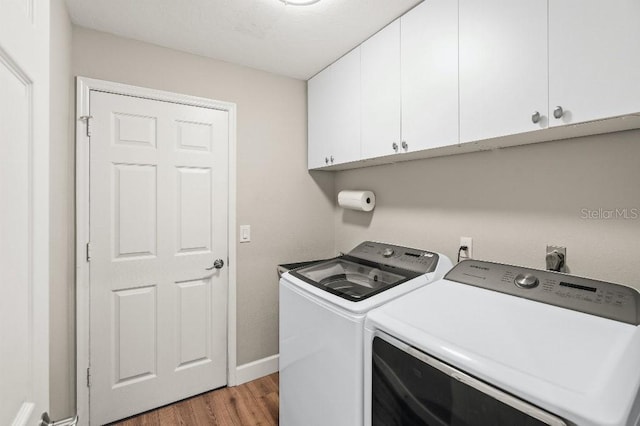 washroom featuring baseboards, wood finished floors, cabinet space, and washer and dryer