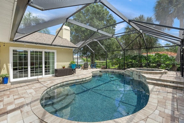 view of swimming pool featuring a pool with connected hot tub, glass enclosure, and a patio