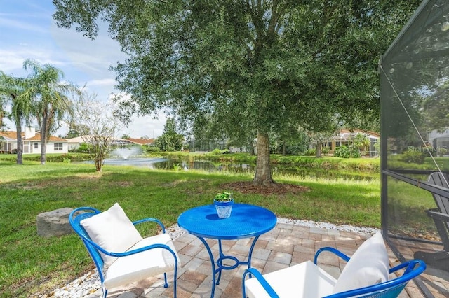 view of patio / terrace featuring a lanai and a water view