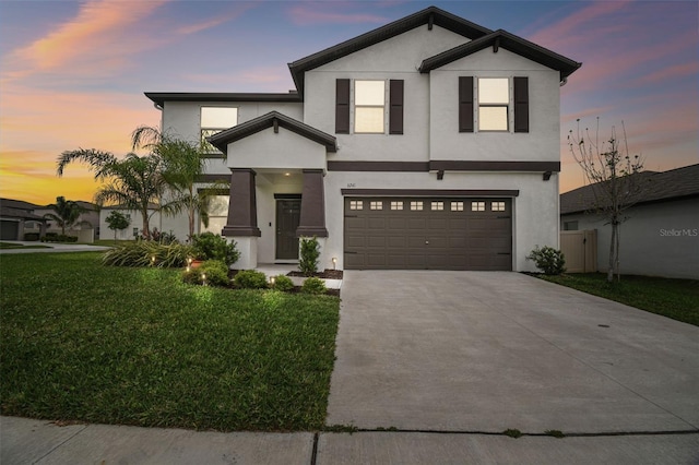 view of front facade featuring a garage, concrete driveway, a front yard, and stucco siding