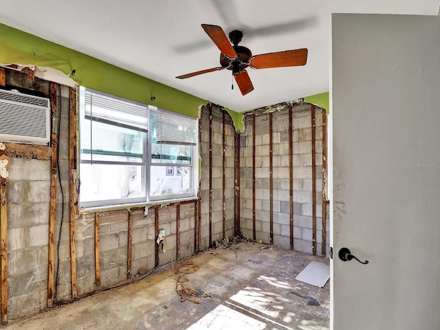 interior space with a wall mounted air conditioner, ceiling fan, and concrete block wall