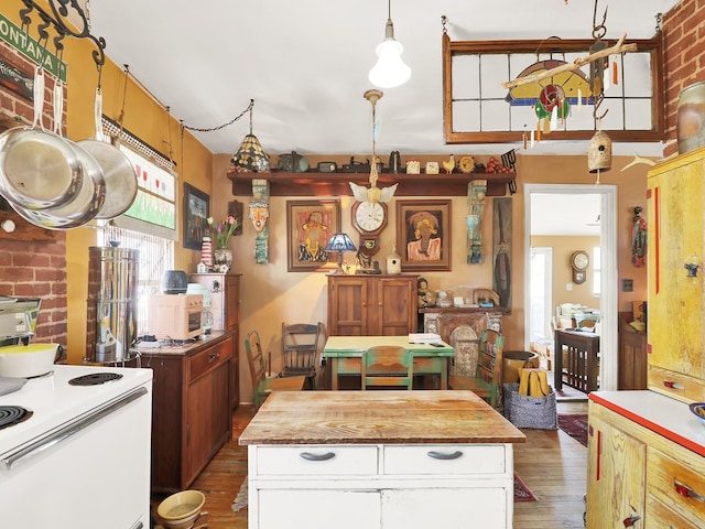 kitchen with hanging light fixtures, white cabinets, white electric stove, and wood finished floors