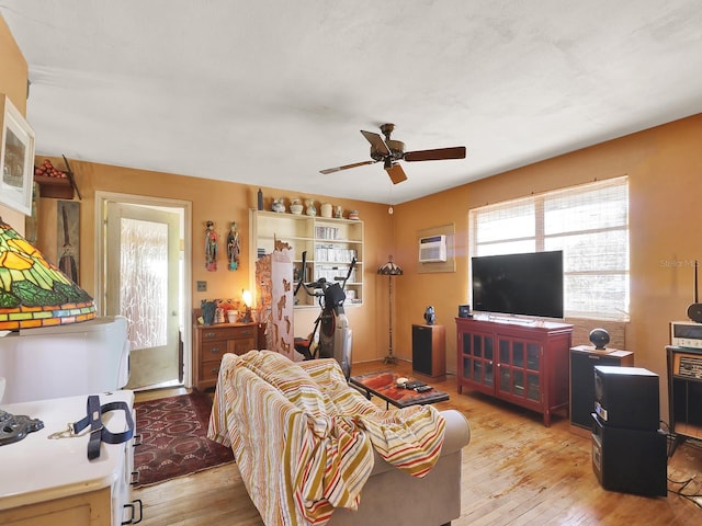 living room with a ceiling fan, light wood-type flooring, and a wall mounted AC