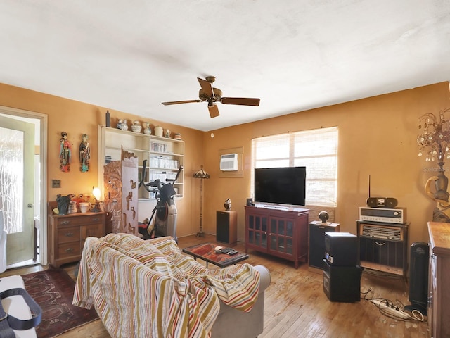 living area featuring a wall mounted AC, a ceiling fan, and hardwood / wood-style flooring