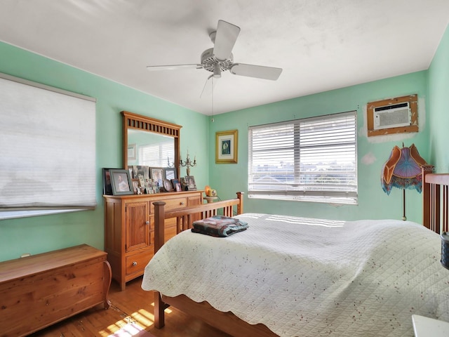 bedroom featuring an AC wall unit, a ceiling fan, and wood finished floors