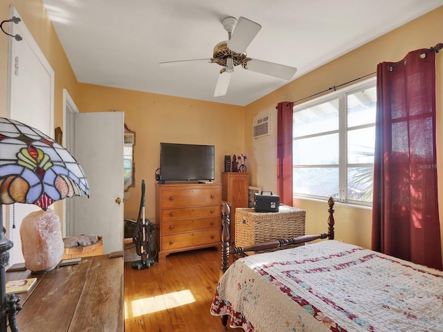 bedroom featuring a ceiling fan, wood finished floors, and a wall mounted air conditioner