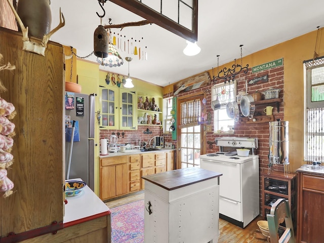 kitchen featuring a kitchen island, light wood-type flooring, decorative backsplash, freestanding refrigerator, and white electric range