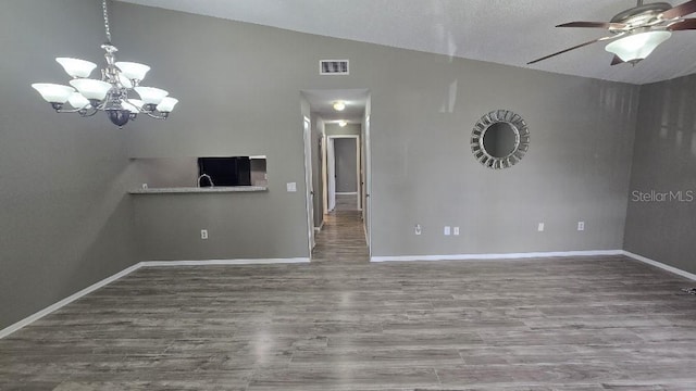 unfurnished living room with baseboards, visible vents, lofted ceiling, wood finished floors, and ceiling fan with notable chandelier