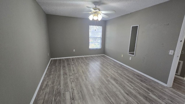 spare room featuring a textured ceiling, baseboards, and wood finished floors