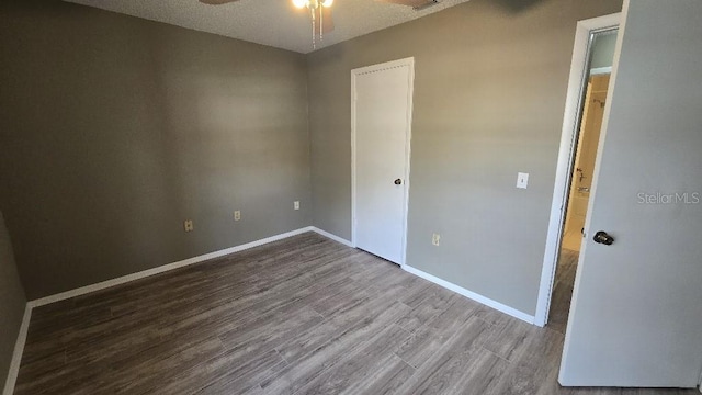 unfurnished bedroom with baseboards and dark wood-type flooring