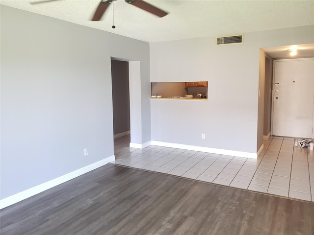 unfurnished room featuring visible vents, ceiling fan, a textured ceiling, wood finished floors, and baseboards