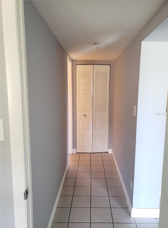 hall featuring light tile patterned flooring and baseboards