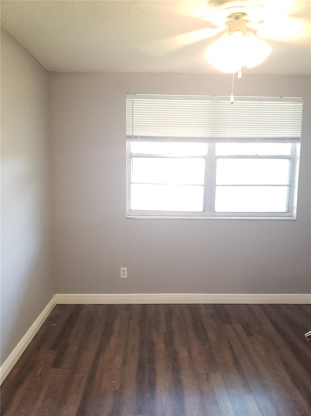 spare room with plenty of natural light, baseboards, and dark wood finished floors