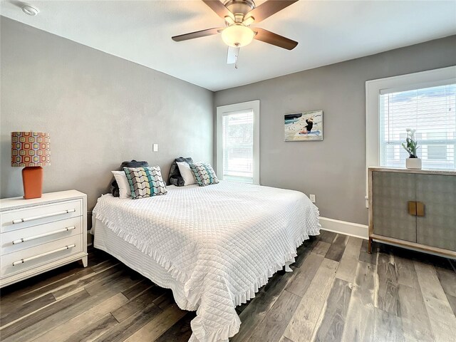 bedroom with dark wood-style floors, a ceiling fan, and baseboards