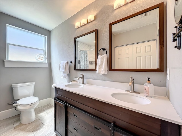 full bath with visible vents, a sink, toilet, and double vanity