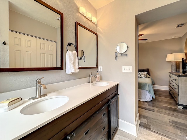 ensuite bathroom featuring visible vents, a sink, baseboards, and double vanity