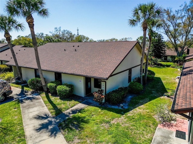 view of front of property with a front lawn, a shingled roof, and stucco siding