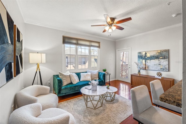 living area with a textured ceiling, wood finished floors, and crown molding