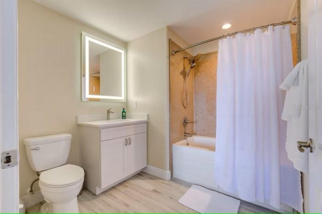 bathroom with baseboards, toilet, wood finished floors, shower / tub combo with curtain, and vanity