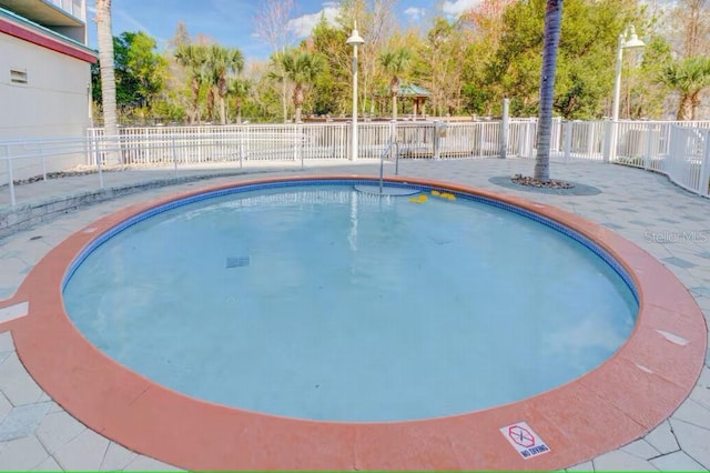 community pool with a fenced backyard and a patio