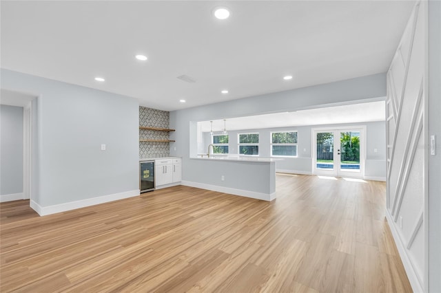 1842 Oklahoma Ave NE, Saint Petersburg, FL 33703 - unfurnished living room with a bar, light wood-style flooring, recessed lighting, and beverage cooler