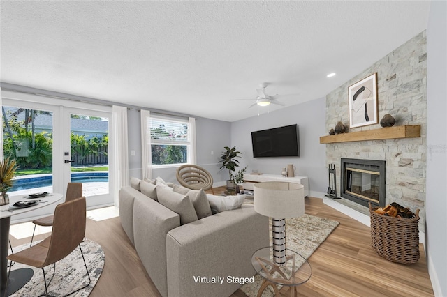 1842 Oklahoma Ave NE, Saint Petersburg, FL 33703 - living area featuring a ceiling fan, a textured ceiling, wood finished floors, a stone fireplace, and baseboards