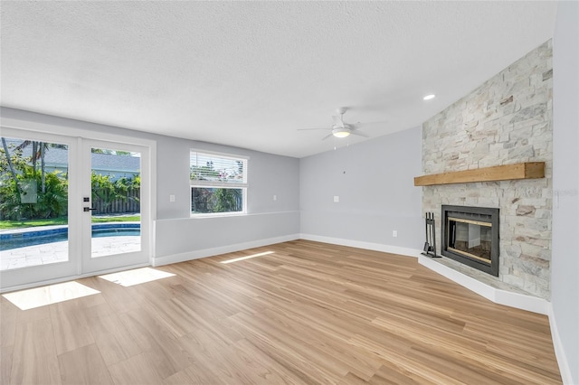 1842 Oklahoma Ave NE, Saint Petersburg, FL 33703 - unfurnished living room featuring a textured ceiling, a fireplace, light wood finished floors, baseboards, and ceiling fan