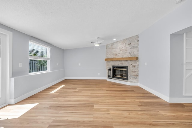 1842 Oklahoma Ave NE, Saint Petersburg, FL 33703 - unfurnished living room with light wood-type flooring, lofted ceiling, a stone fireplace, a textured ceiling, and a ceiling fan