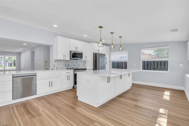 1842 Oklahoma Ave NE, Saint Petersburg, FL 33703 - kitchen with decorative backsplash, light wood-style flooring, appliances with stainless steel finishes, and light countertops