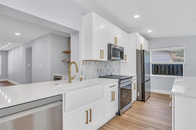 1842 Oklahoma Ave NE, Saint Petersburg, FL 33703 - kitchen featuring light wood-type flooring, a sink, white cabinetry, appliances with stainless steel finishes, and decorative backsplash