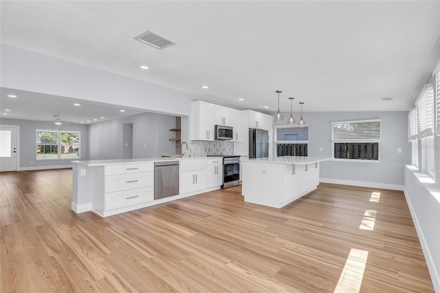 1842 Oklahoma Ave NE, Saint Petersburg, FL 33703 - kitchen featuring visible vents, open floor plan, light wood-style flooring, appliances with stainless steel finishes, and white cabinetry
