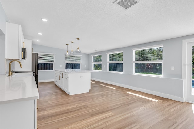 1842 Oklahoma Ave NE, Saint Petersburg, FL 33703 - kitchen featuring light wood-type flooring, visible vents, white cabinets, and light countertops