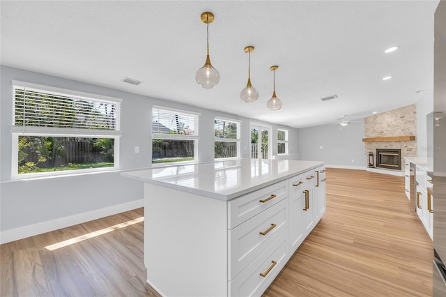 1842 Oklahoma Ave NE, Saint Petersburg, FL 33703 - kitchen featuring a fireplace, light wood-style floors, light countertops, and white cabinets