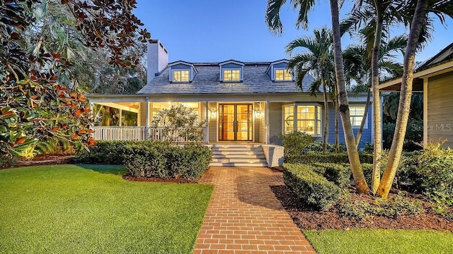 view of front of property with a porch, french doors, a chimney, and a front lawn