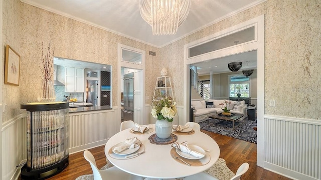 dining space featuring wallpapered walls, ornamental molding, dark wood-style flooring, and a wainscoted wall