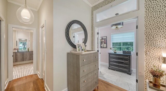 corridor with ornamental molding, light wood-type flooring, and baseboards