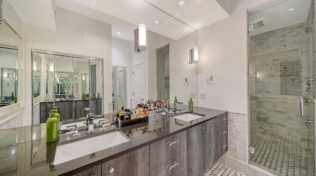 bathroom with double vanity, a shower stall, and a sink