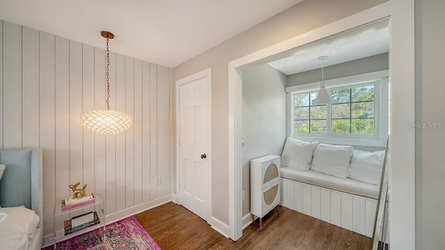 hallway featuring heating unit, wooden walls, baseboards, and wood finished floors