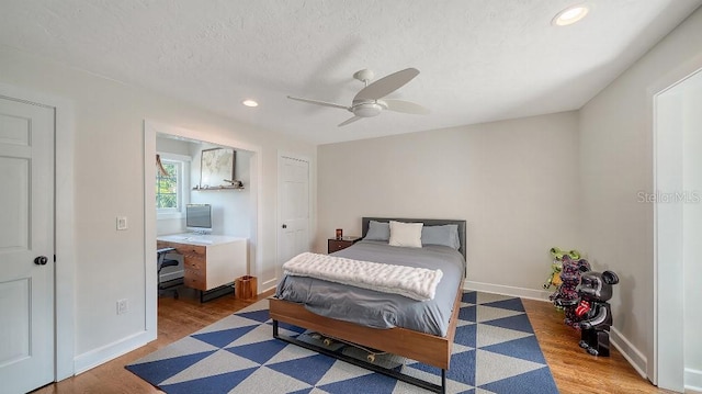 bedroom featuring light wood-type flooring, baseboards, a textured ceiling, and recessed lighting