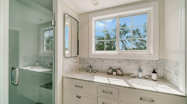 bathroom featuring a stall shower, a sink, decorative backsplash, and double vanity