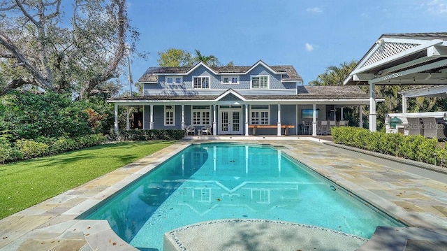 rear view of property with a yard, a patio, french doors, and an outdoor pool