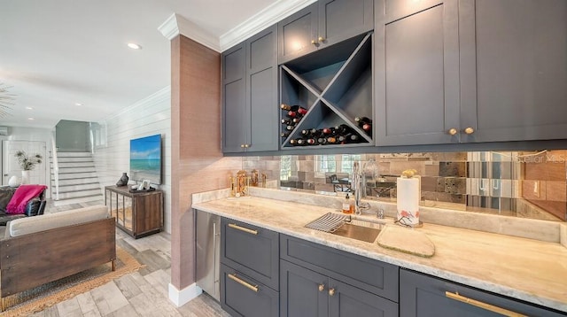 kitchen featuring ornamental molding, light wood-type flooring, a sink, and gray cabinetry