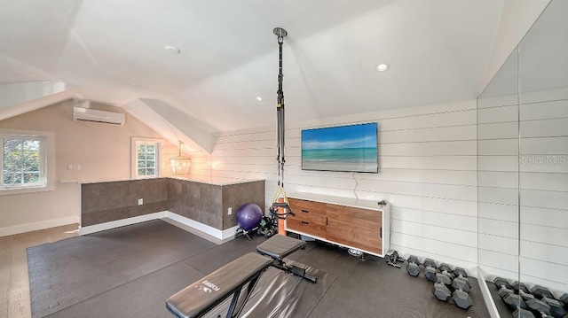 exercise room with a wall unit AC, baseboards, and lofted ceiling