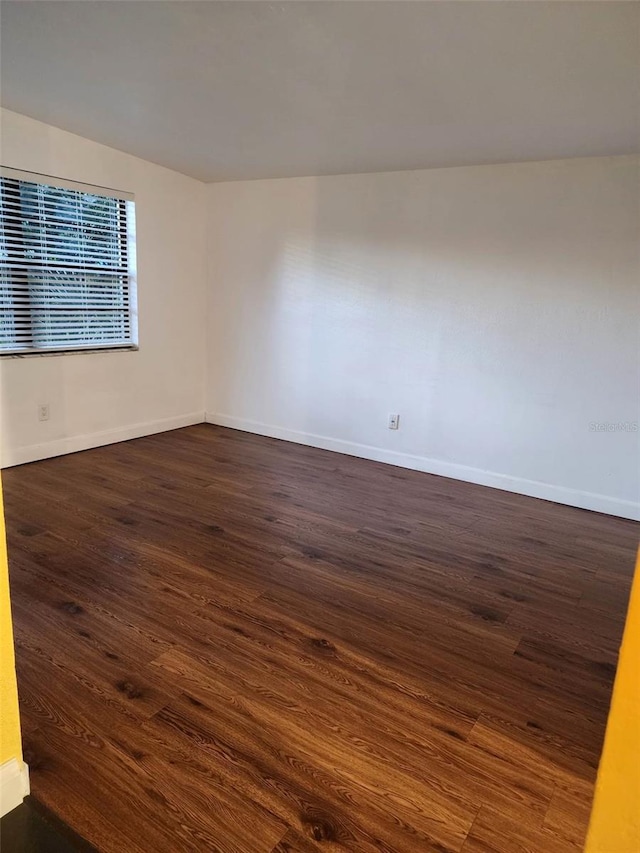 unfurnished room with baseboards and dark wood-style flooring