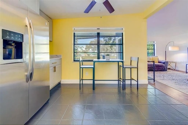 kitchen with white cabinets, dark tile patterned floors, stainless steel refrigerator with ice dispenser, and ceiling fan