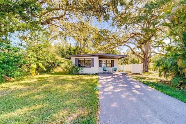 view of front facade featuring stucco siding, driveway, a front yard, and fence