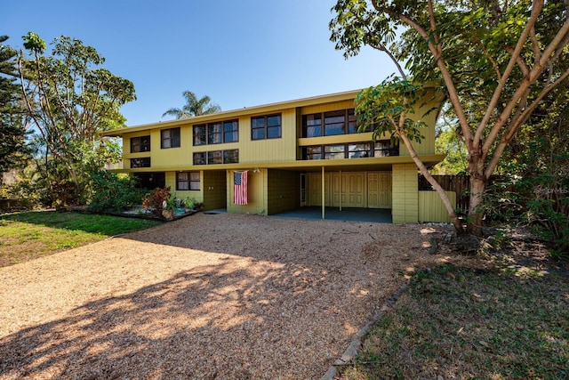 view of front of property with an attached carport, gravel driveway, and fence